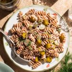 Pickle pasta salad on a serving plate with a spoon.