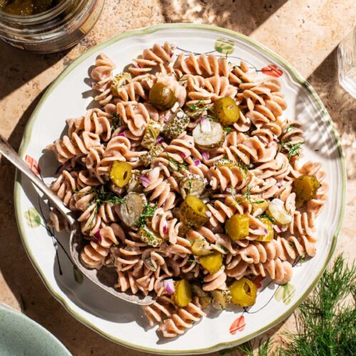 Pickle pasta salad on a serving plate with a spoon.