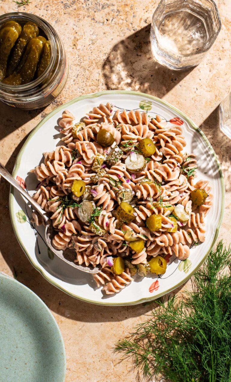 Pickle pasta salad on a serving plate with a spoon.