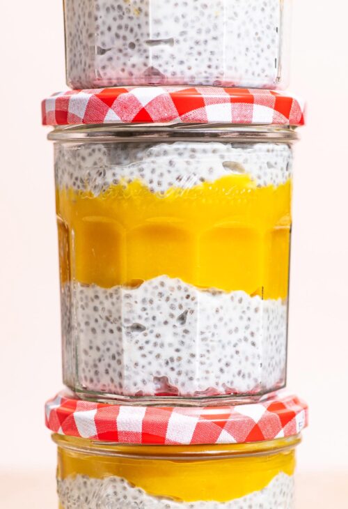 Stack of three jars of chia pudding layered with mango puree.