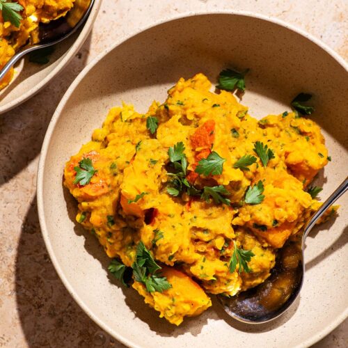 Two bowls with a thick lentil curry topped with parsley.