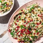 Pink serving platter with rice, parsley, and pomegranate salad.