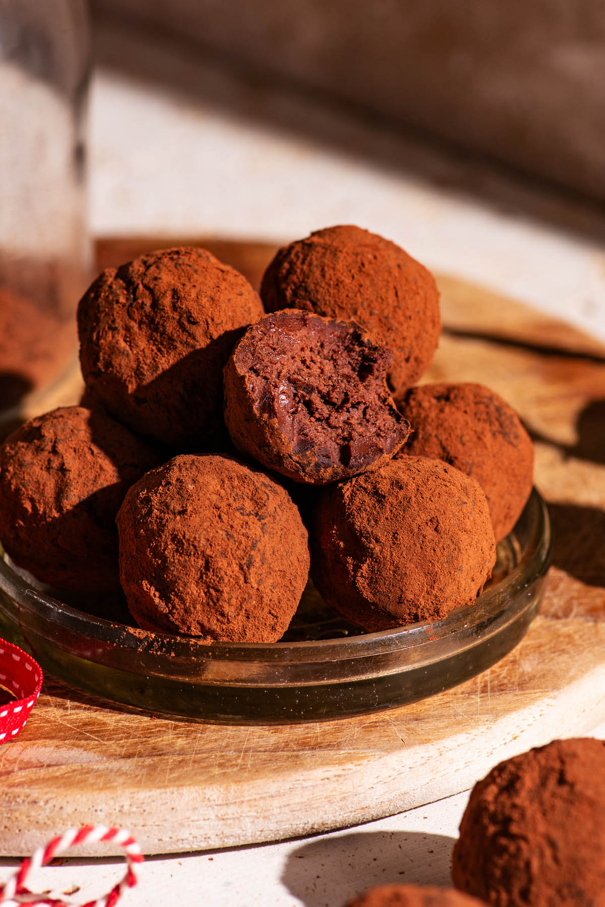 Several cocoa-coated truffles piled together, one with a bite taken out.