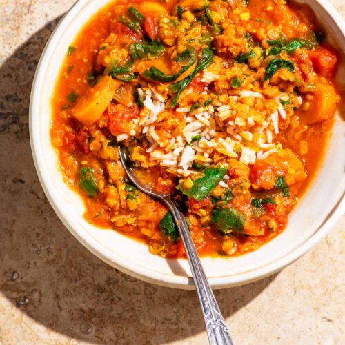 Bowl of red lentil soup in bright direct light on a stone background.