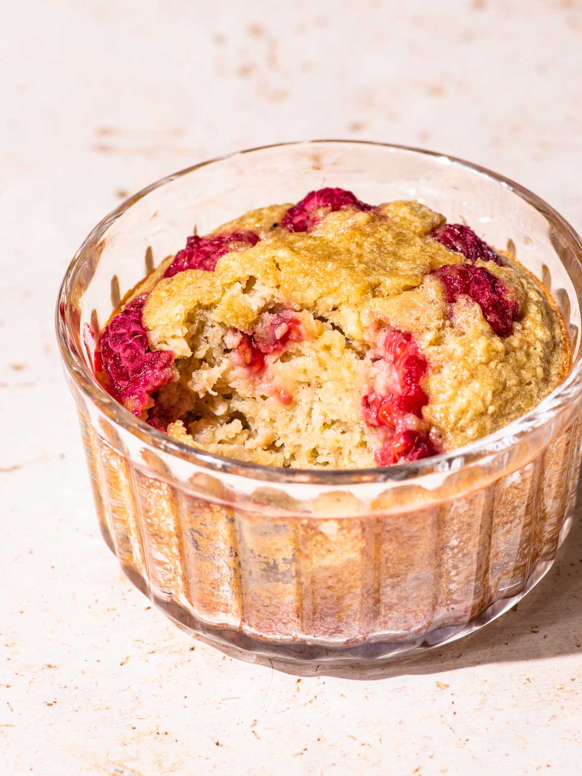 Close up of baked oats in a small glass ramekin with a spoonful removed to show interior texture.