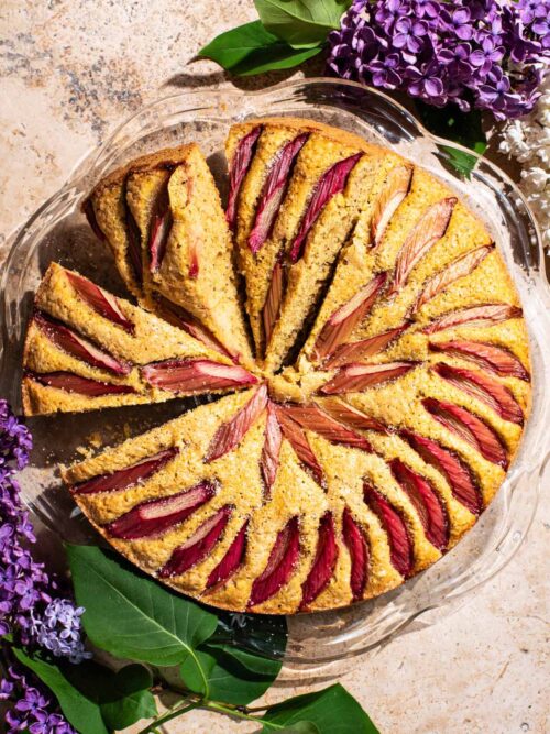 A rhubarb-topped cake with three slices cut, each on a slight angle.