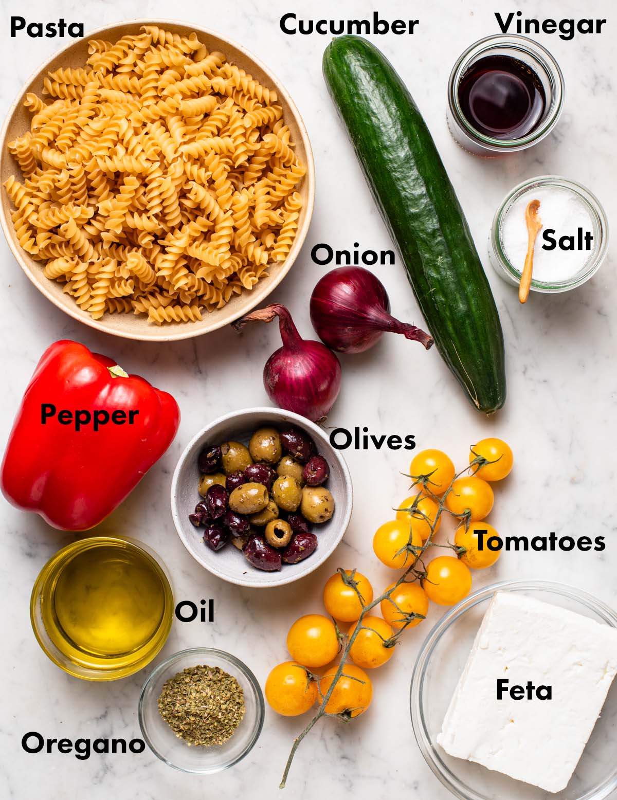 Greek pasta salad ingredients with labels.