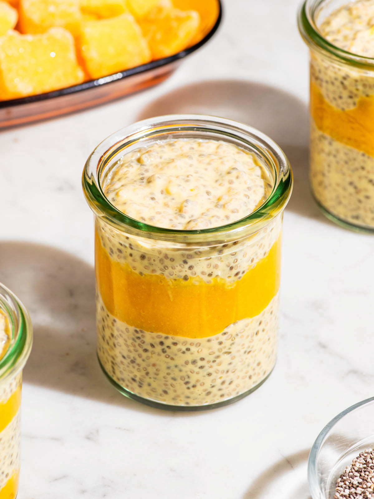 Mango chia seed pudding in small glass jars with mango puree layered in.