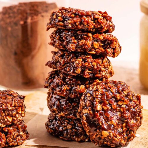 A stack of no-bake chocolate cookies on a small wooden cutting board.