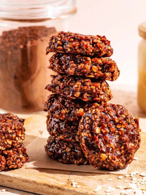 A stack of no-bake chocolate cookies on a small wooden cutting board.