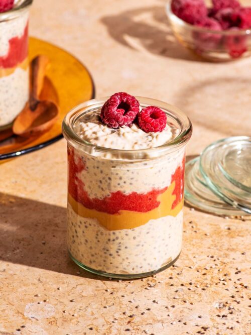 Chia pudding in small glass jars, layered with raspberry jam and peanut butter.