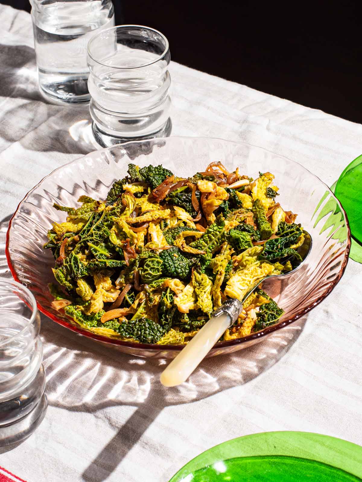 A glass serving bowl of cooked savoy cabbage with onions.