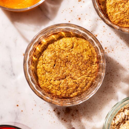 Orange-hued baked oats in small glass ramekins.