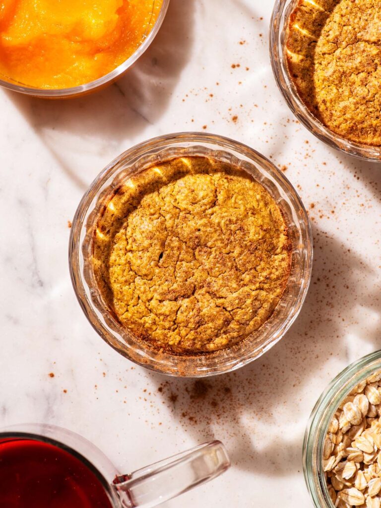 Orange-hued baked oats in small glass ramekins.