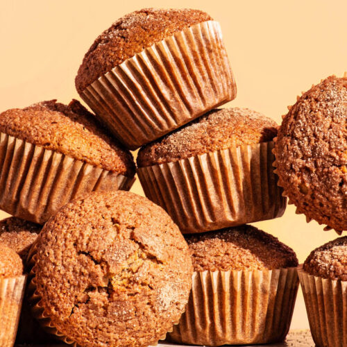Several plain muffins in paper liners piled up together.