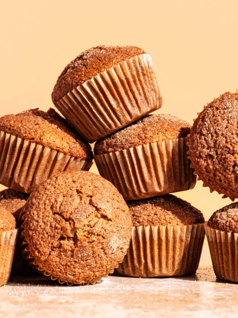 Several plain muffins in paper liners piled up together.