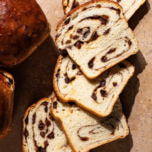 Raisin bread slices with loaves around.